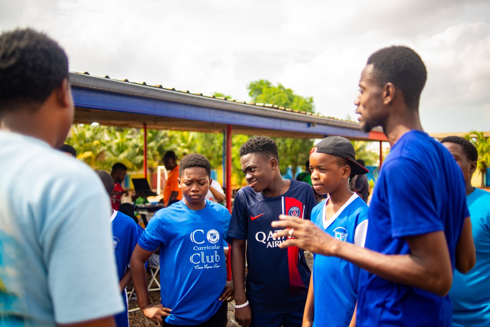 Learners in co-curricular club T-shirts talking outdoors