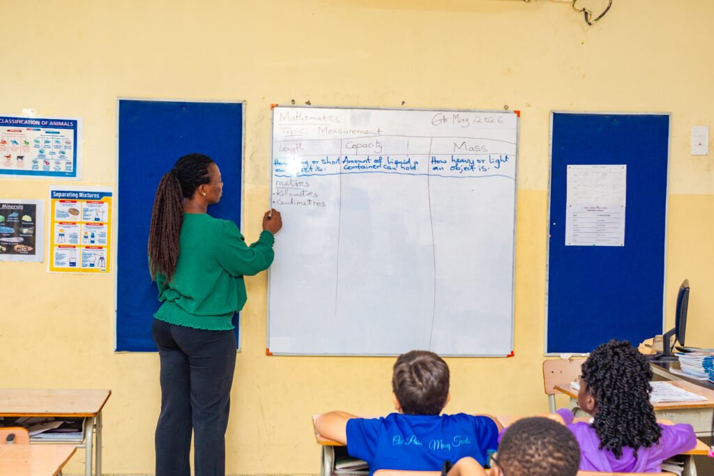 Teacher writing on the whiteboard in a primary classroom